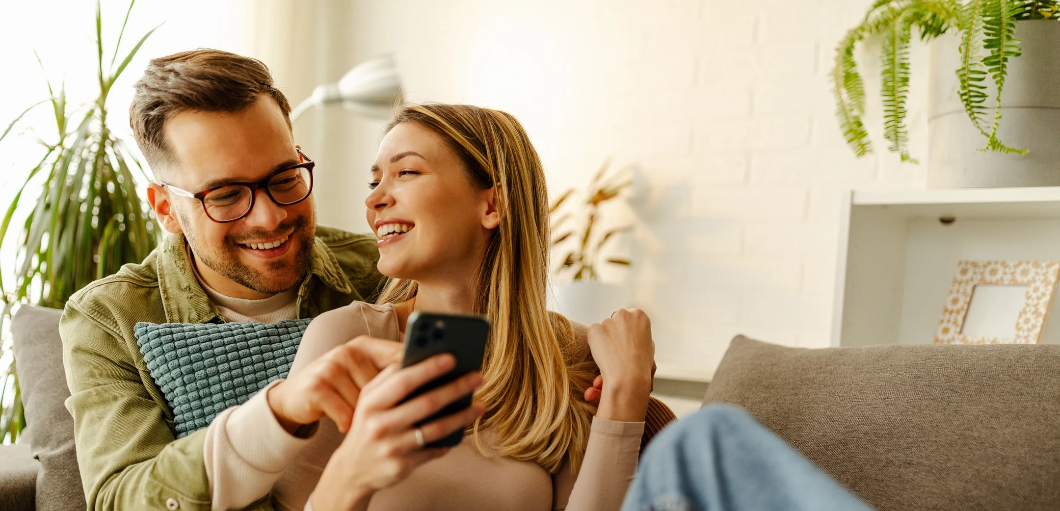 couple lounging on couch looking at phone