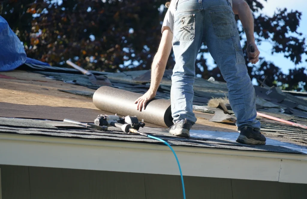 contractor rolling underlayment over rooftop before installing shingles