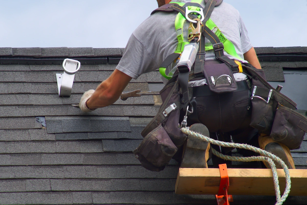professional worker repairing storm damage on shingles