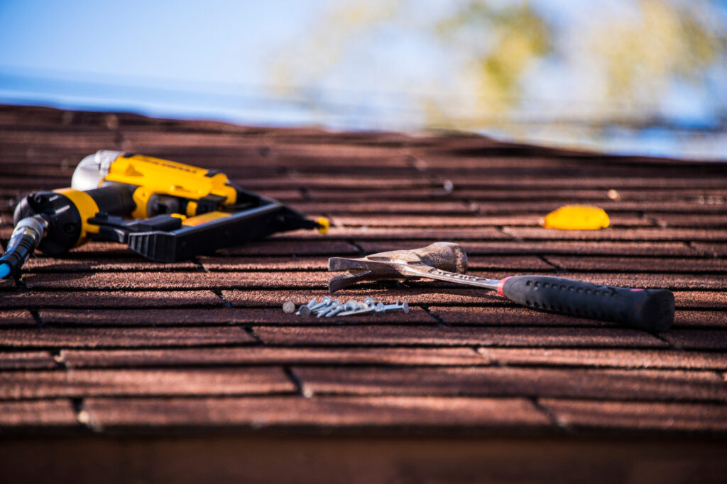 Tools on roof: hand drill, nails, hammer - construction or repair in progress