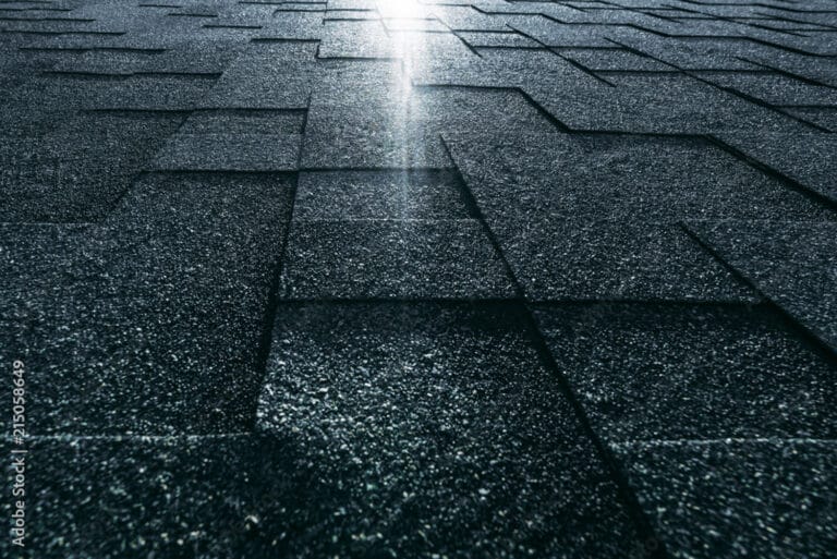 Roof with shingles and vents under clear sky, representing suburban or urban housing architecture.